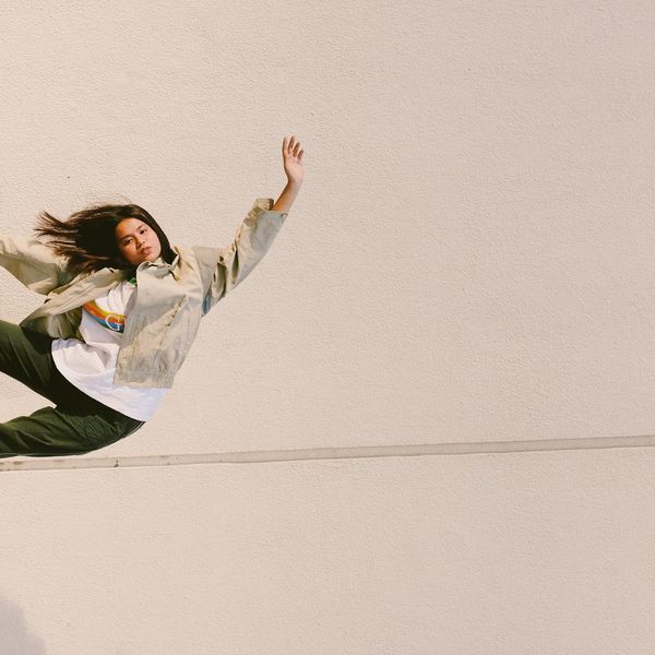 Person in a balancing yoga pose against a minimal background.