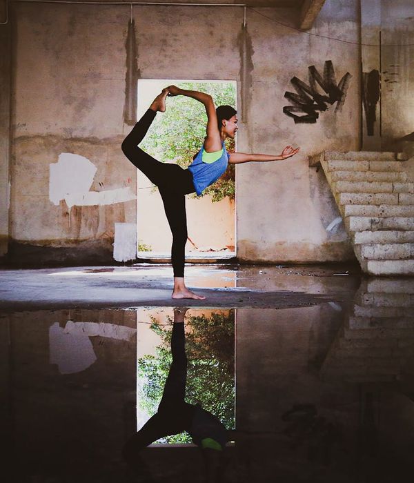 Woman in a calm stretching pose in a dark room with emerald light.